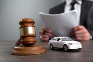 Car accident lawyer with toy car and gavel on table
