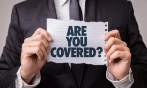 A man suit holding piece of paper text 'Are You Covered'