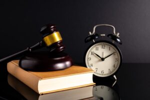 Wooden gavel lying on a book beside a clock 