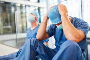 Two exhausted and desperate surgeons as signs of congestion and error