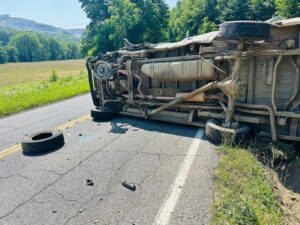 Motor vehicle accident scene where a cargo van was involved in a head on collision with a logging truck on a country road. 
