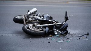 A dramatic motorcycle accident scene, showcasing a fallen bike amidst scattered glass and debris on the road