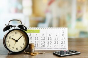 A clock, calendar, calculator and coins on the table 
