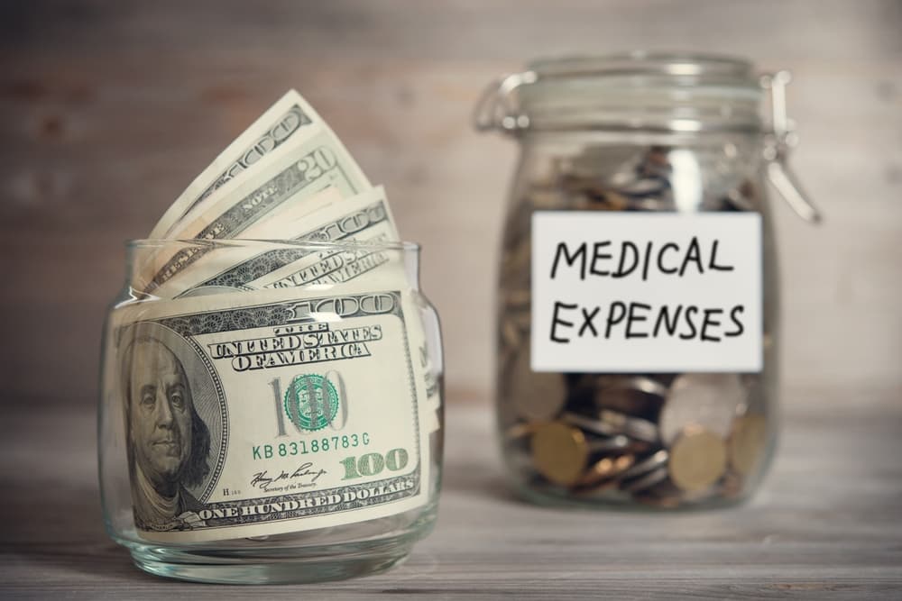 Dollars and coins in glass jar with medical expenses label