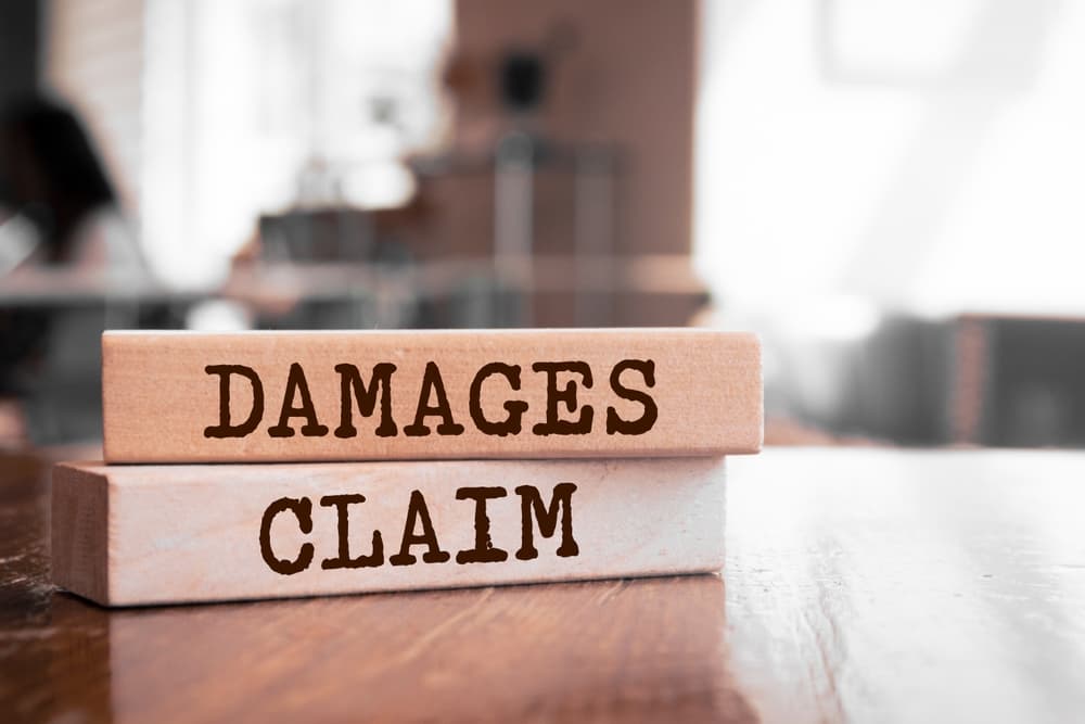 Damages & Claim written on wood block