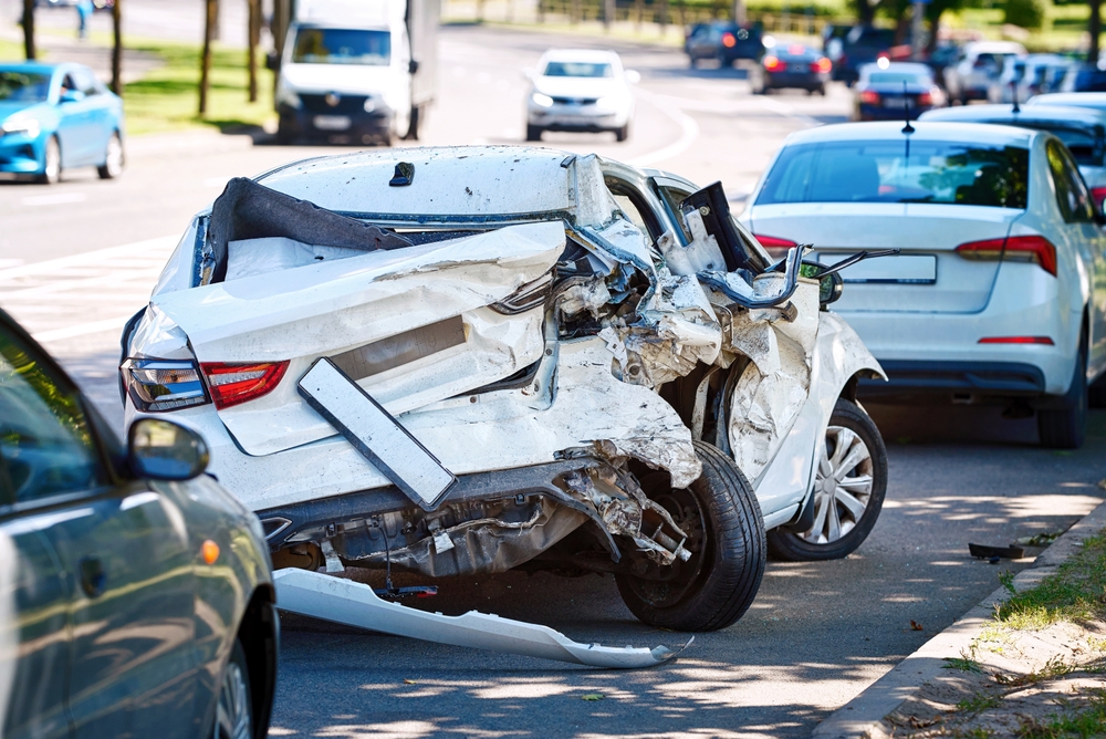 A heavily damaged white car after a serious collision on a city street, representing the aftermath of a fatal car accident in Montana.